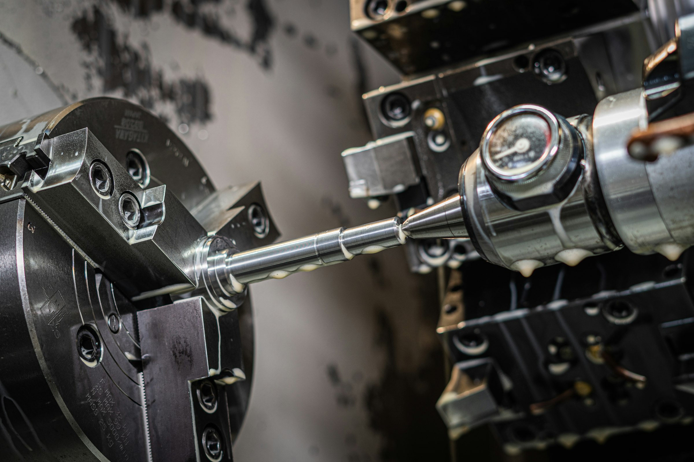 A CNC spindle cutting into a block of aluminum, coolant beading on the fresh-cut face