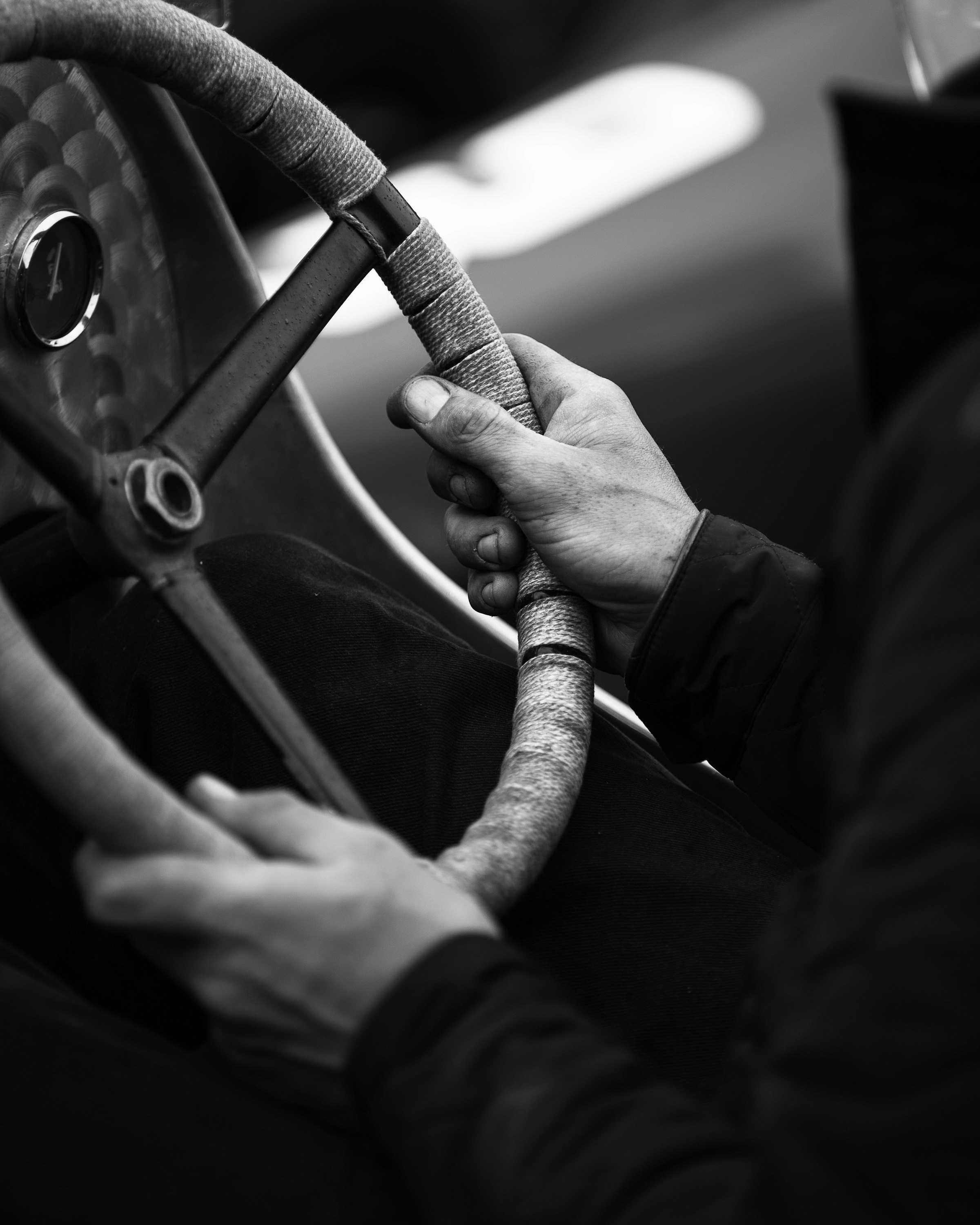Black and white photo of a driver's hands resting on a steering wheel